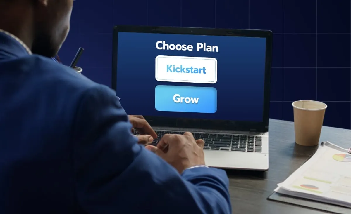 A man working at a laptop that shows a 'Choose Plan' screen with 'Kickstart' and 'Grow' options.