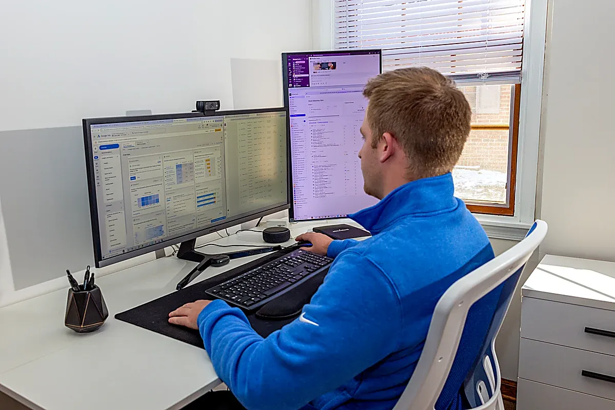 An Elevated Audience strategist reviewing an HVAC client's search and lead reporting on two screens